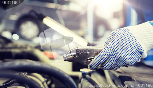 Image of mechanic man with pliers repairing car at workshop