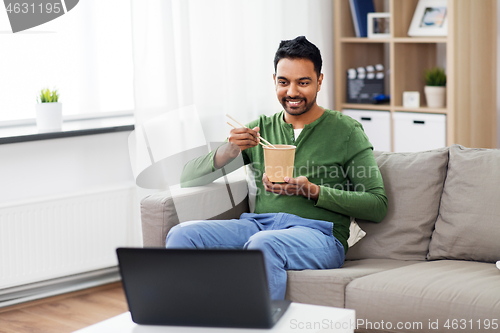 Image of indian man with laptop eating takeout food at home