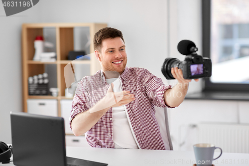 Image of male blogger with camera videoblogging at office