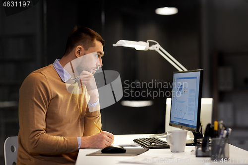 Image of man with notepad working at night office