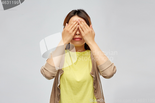 Image of young woman with eyes closed by hands