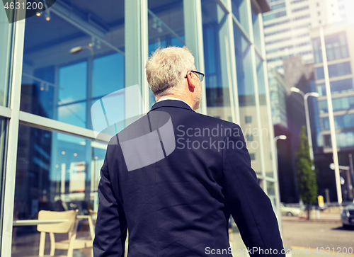 Image of senior businessman walking along city street