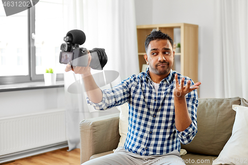 Image of male video blogger with camera blogging at home