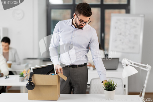 Image of sad fired male office worker with personal stuff