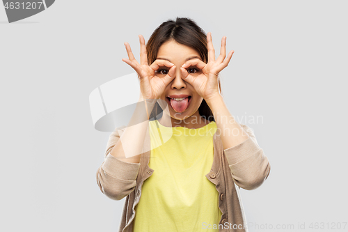 Image of smiling asian woman looking through finger glasses