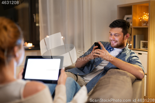 Image of couple with tablet computer and smartphone at home