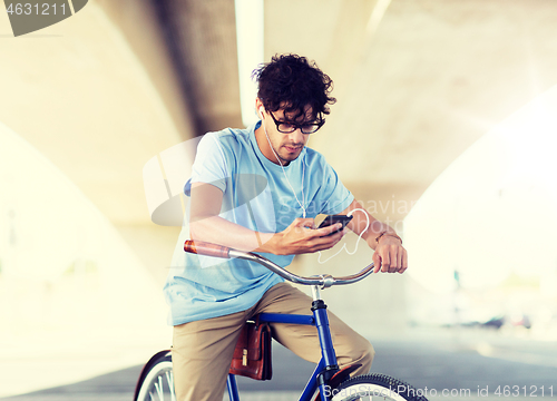 Image of man with smartphone and earphones on bicycle