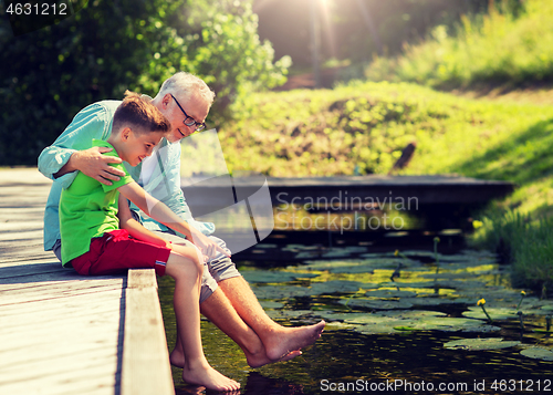 Image of grandfather and grandson sitting on river berth