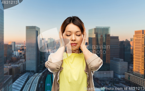 Image of asian woman closing ears by hands in tokyo city