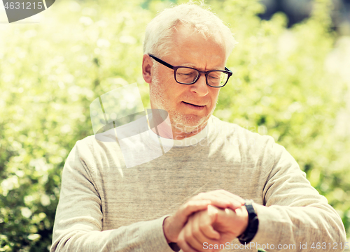 Image of senior man checking time on his wristwatch