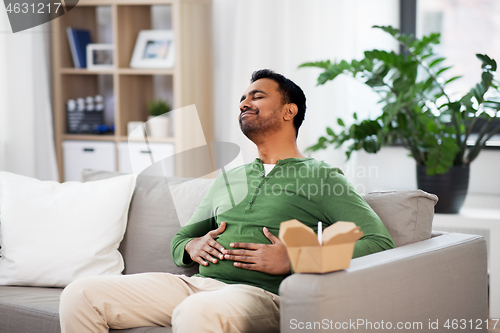 Image of pleased indian man eating takeaway food at home