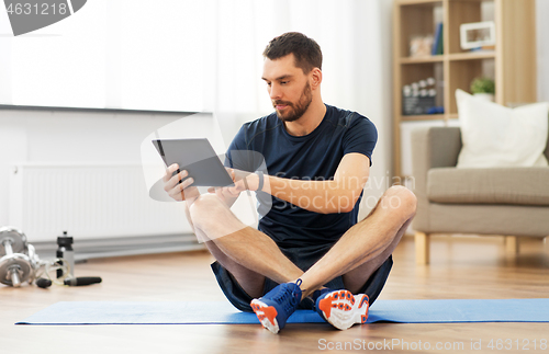 Image of man with tablet computer on exercise mat at home