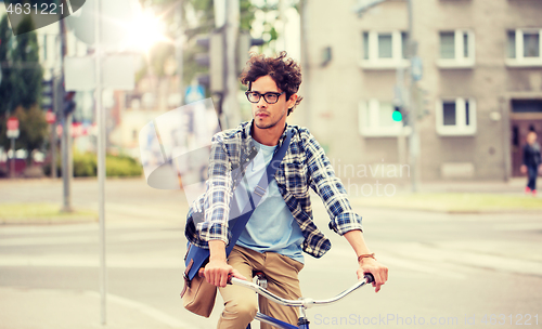 Image of young hipster man with bag riding fixed gear bike