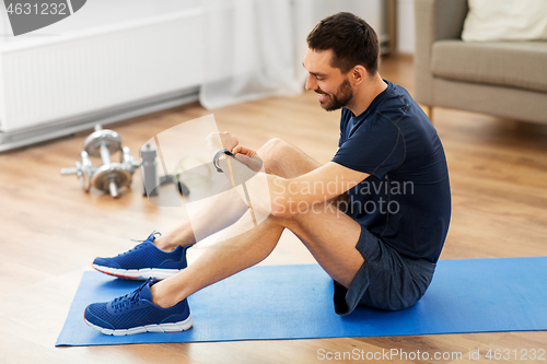 Image of smiling man with fitness tracker exercising at home