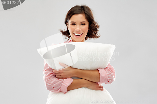 Image of happy young woman in pajama hugging pillow