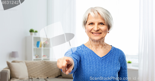 Image of happy senior woman pointing finger to you at home