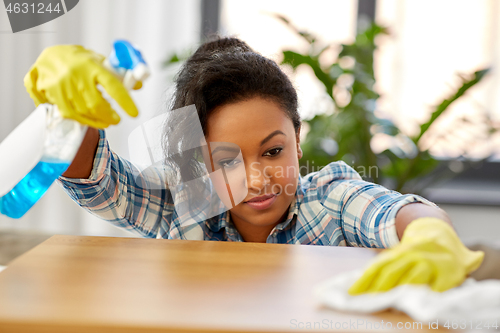 Image of african american woman cleaning table at home