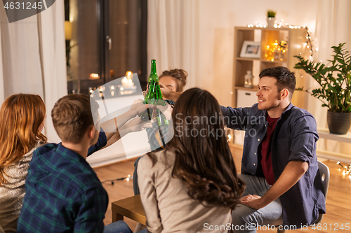 Image of friends clinking drinks at home in evening