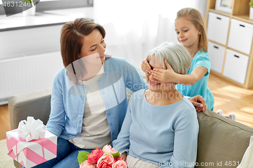 Image of mother and daughter greeting grandmother at home