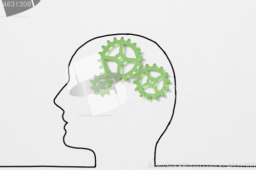 Image of Drawn outline of human head with green clockwork as a working brain.