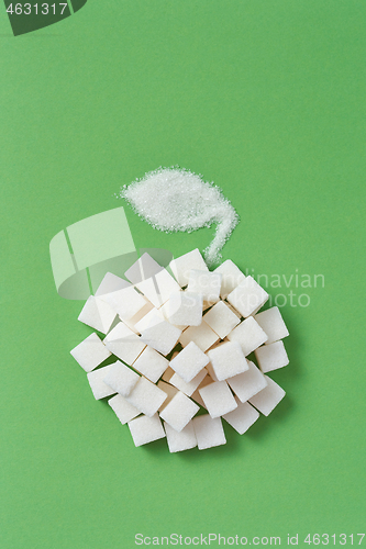 Image of Handmade apple from sugar cubes and leaf on a green background.