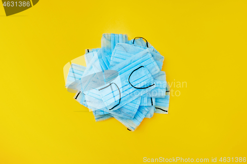 Image of Heap of medical masks on a yellow background. Top view.