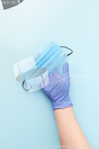 Image of Medical mask on a woman\'s hand in protective rubber glove. Top view.