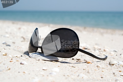 Image of The black sunglasses lying on a beach