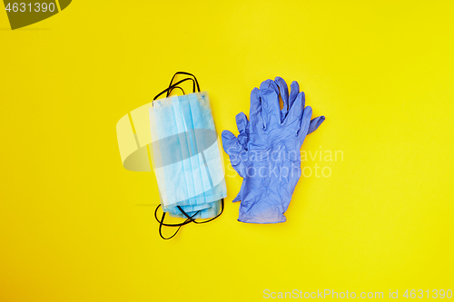 Image of Two piles from medical masks and protective gloves on a yellow background.