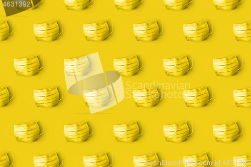 Image of Yellow painted protective medical masks on the same color background.