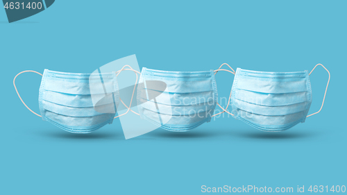 Image of Three floating medical masks above blue background with shadows.