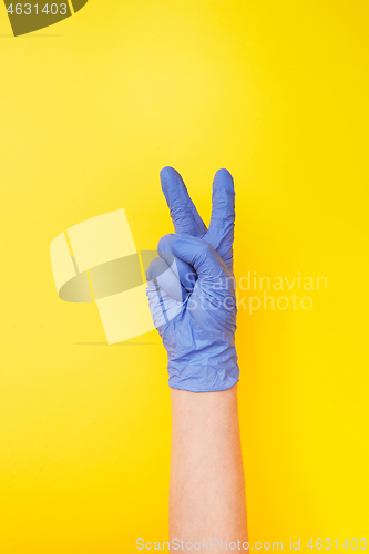 Image of Sign victory made female\'s hand in rubber protective glove.