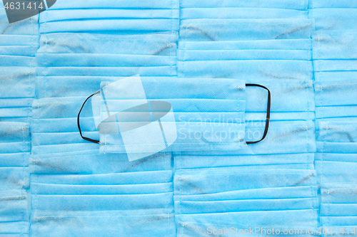 Image of Blue medical mask on the same masks and color background .