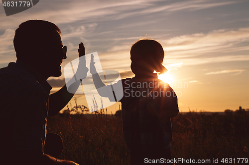 Image of Father and son playing in the park at the sunset time.