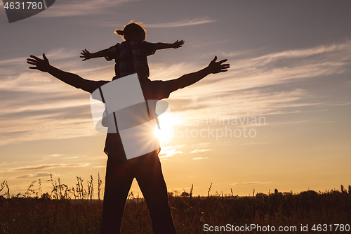 Image of Father and son playing in the park at the sunset time.