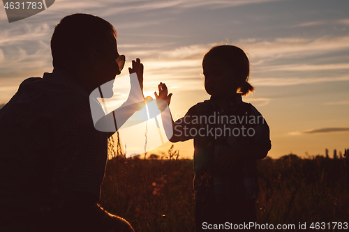 Image of Father and son playing in the park at the sunset time.