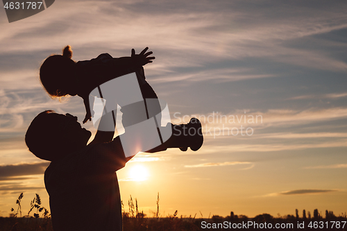 Image of Father and son playing in the park at the sunset time.