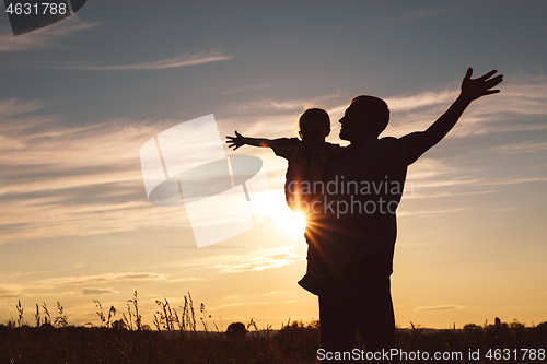 Image of Father and son playing in the park at the sunset time.