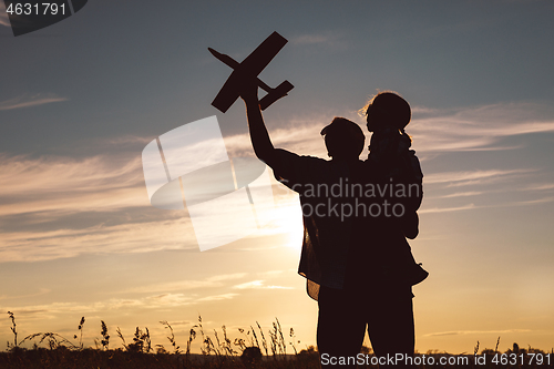 Image of Father and son playing in the park at the sunset time.