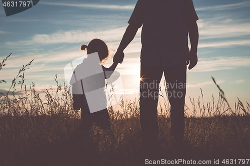 Image of Father and sad son standing in the park at the sunset time.