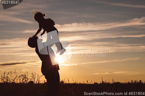 Image of Father and son playing in the park at the sunset time.