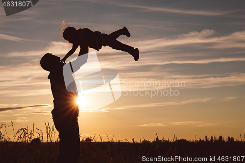 Image of Father and son playing in the park at the sunset time.