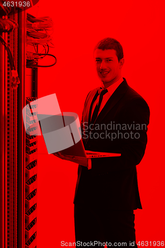 Image of businessman with laptop in network server room