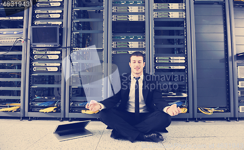 Image of businessman with laptop in network server room