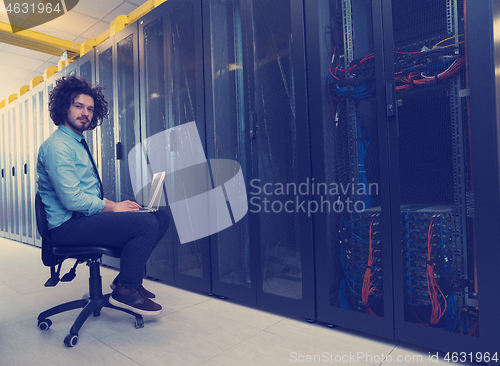 Image of engineer working on a laptop in server room