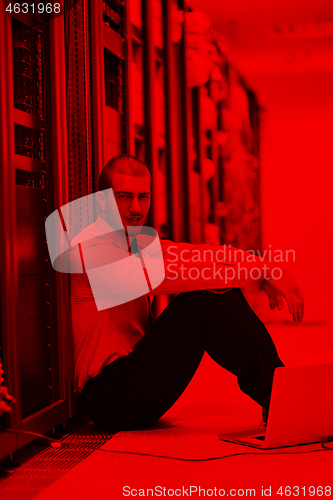 Image of businessman with laptop in network server room