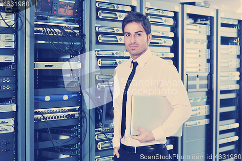 Image of businessman with laptop in network server room