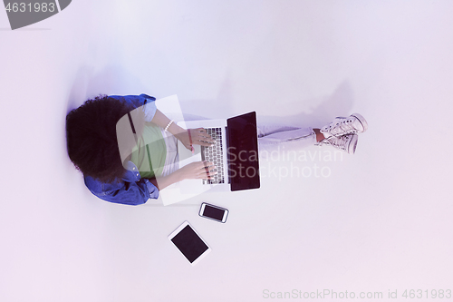 Image of african american woman sitting on floor with laptop top view