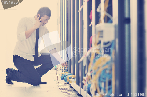 Image of it engeneer talking by phone at network room