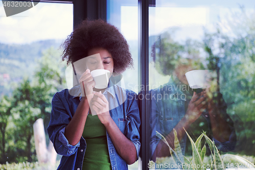 Image of African American woman drinking coffee looking out the window